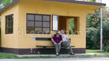 一对夫妇坐在橙色房子前面的长凳上